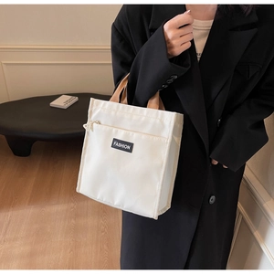 Close-up of white waterproof lunch bag with fashion label and khaki handles