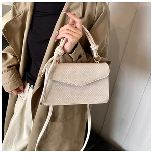Dettaglio della borsa beige testurizzata con trama a rombi e fibbie in metallo oro