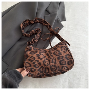Detailed view of leopard print faux fur shoulder bag with ruched handle on grey blazer