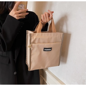 Detail of minimalist beige fabric tote bag with brown woven handles and Fashion label