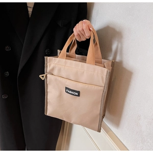 Detailed view of beige canvas tote bag with front zipper and brown handles