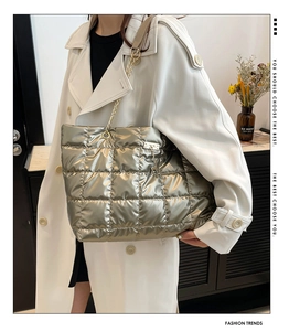 Detail of silver metallic quilted tote bag with chain strap and gold kitten charm accent