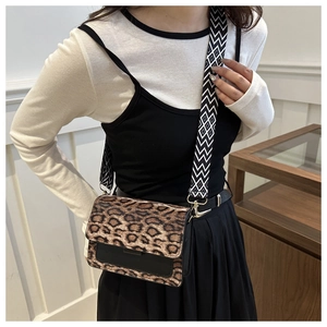 Detail of leopard print crossbody bag with wide woven strap and leather flap cover