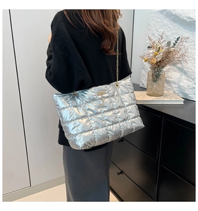 Detail of silver quilted tote bag with metallic finish and gold chain strap