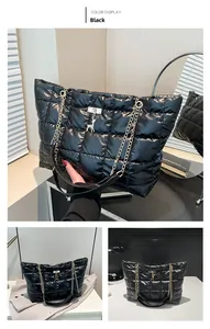 Detail of black quilted nylon tote bag with golden chain and deer pendant charm