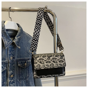 Detail of leopard print crossbody bag with wide geometric strap and golden hardware
