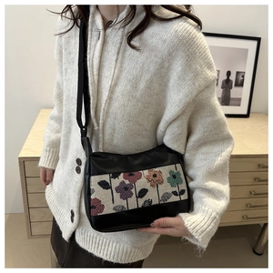 Detail van een zwarte tote bag met bloemen jacquard paneel en smalle schouderriem