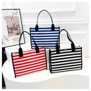 Tre borse tote in tela a righe blu, rosse e nere su un supporto bianco elegante