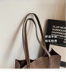 Detail of a brown leather tote bag showing the fashion logo and durable handle design