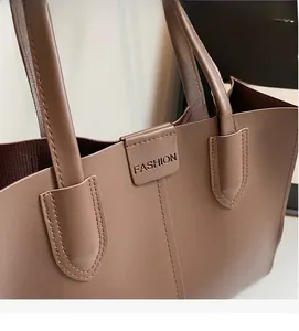 Detailed close-up of dark brown leather tote showing fine texture and fashion engraving