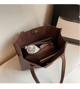 Detailed interior of large capacity brown tote bag with magnetic closure and daily items
