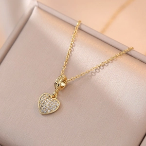 Golden heart pendant necklace with shimmering crystals on a champagne jewelry box