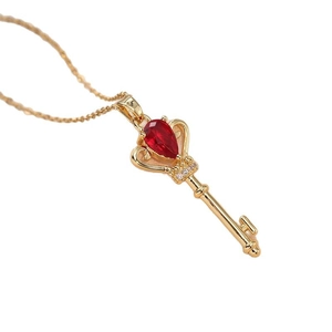 Gold key pendant necklace featuring a sparkling pear-cut red zircon and fine chain