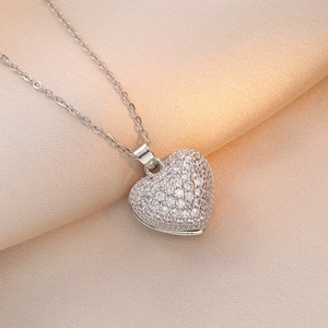 Elegant silver heart pendant necklace with shimmering cubic zirconia on champagne silk
