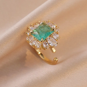 Anello regolabile dorato con zircone verde smeraldo e alone di cristalli trasparenti fini