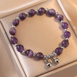 Bracelet en améthyste lavande avec perles argentées et clochettes sur boîte à bijoux