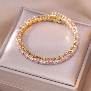Nahaufnahme des goldenen Armbands mit herzförmigen rosa und klaren Zirkon-Kristallen