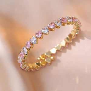 Nahaufnahme von rosa und weißen Herz-Zirkonia Steinen in einem vergoldeten Armband