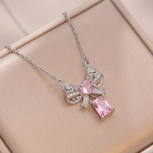 Collier nœud argenté avec pierre rose en cœur et cristaux pavés dans son coffret cadeau