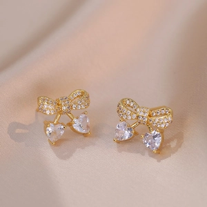 Golden bow stud earrings with sparkling pavé diamonds and heart-shaped zircon pendants