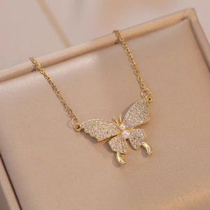 Elegante collana a farfalla dorata con zirconi e perle su scatola portagioie