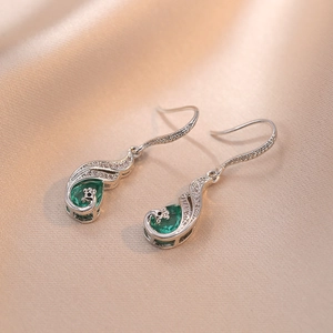 Elegant silver peacock feather earrings with pear-cut emerald gemstones and pavé accents