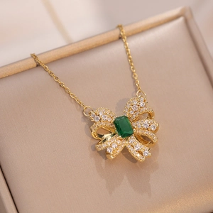Collier nœud doré avec émeraude et zircons brillants sur support d'exposition