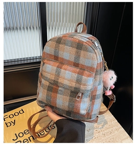 Detail of plaid tweed mini backpack with brown leather trim and pink pompom keychain