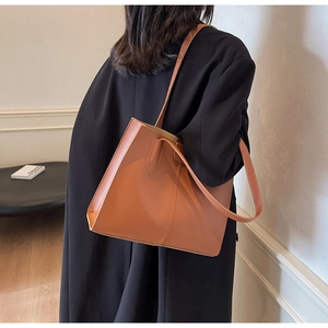 Brown leather tote bag styled with a black coat for a sophisticated commuter look