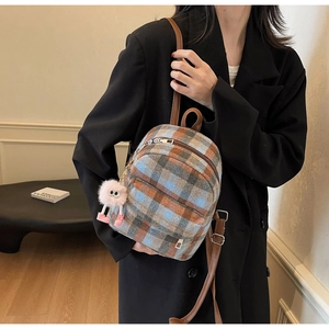 Detail of checkered plaid mini backpack with pink plush monster charm and leather straps