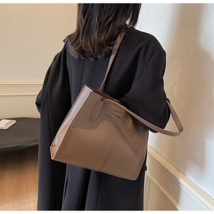 Detail of mocha brown leather tote bag with FASHION embossed tag and slim strap