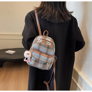 Classic plaid small backpack with wool texture and cute plush charm on a model
