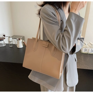 Detail of beige leather tote bag with FASHION text and vertical stitching decoration
