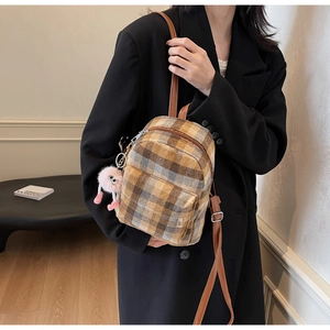 Close-up of wool plaid mini backpack with leather straps and cute plush pendant
