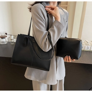 Detail of black leather tote bag set featuring a matching inner pouch and shoulder strap