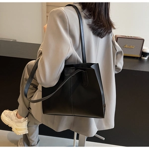 Close-up of black PU leather tote bag with FASHION label and dual shoulder straps