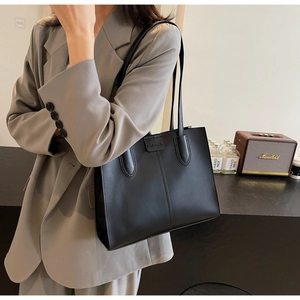 Chic black leather tote bag with FASHION embossed logo shown on a model for daily commute