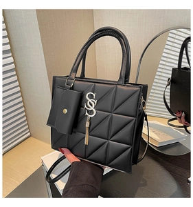 Detailed view of black quilted leather handbag with silver metal logo and fringe tassel