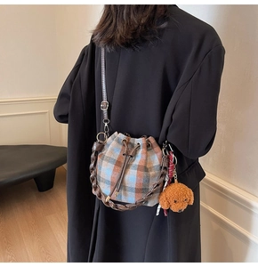 Detail of plaid drawstring bucket bag with leather strap and plush teddy charm