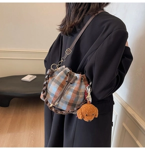 Detail of checkered tweed bucket bag with brown leather drawstring and teddy charm