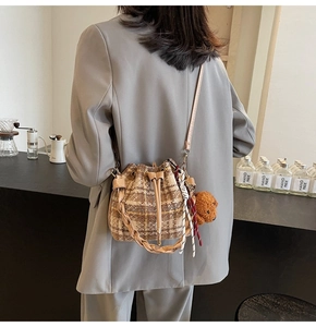 Detailed side view of vintage plaid bucket bag with braided handle and bear charm