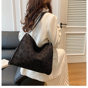 Gros plan d'un grand sac hobo noir avec motifs floraux discrets sur tissu texturé