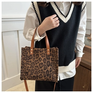 Detail of leopard print tote bag featuring gold rivets and brown leather strap handles