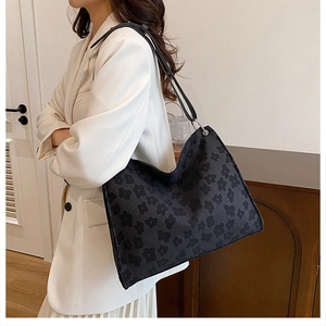 Détail d'un sac cabas noir avec motif floral et bandoulières en cuir solides