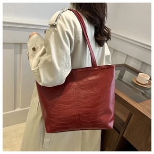 Side view of red crocodile pattern tote bag with 3D rib bone relief design on model
