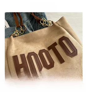 Detail of HOOTO beige tote bag featuring brown lettering and metal chain strap accents