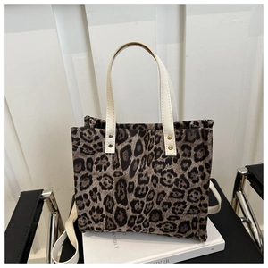 Detail of leopard print tote bag with white handles and secure metal rivet hardware