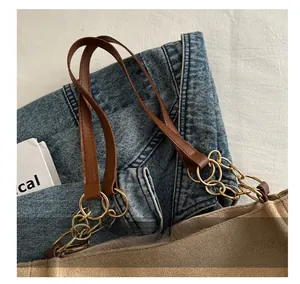 Detail of brown suede tote bag featuring premium leather handles and golden metal chain link