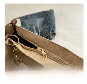 Detailed macro view of smooth gold zipper and leather trim on beige tote bag