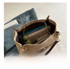 Macro view of beige tote bag interior capacity with leather straps and chain details